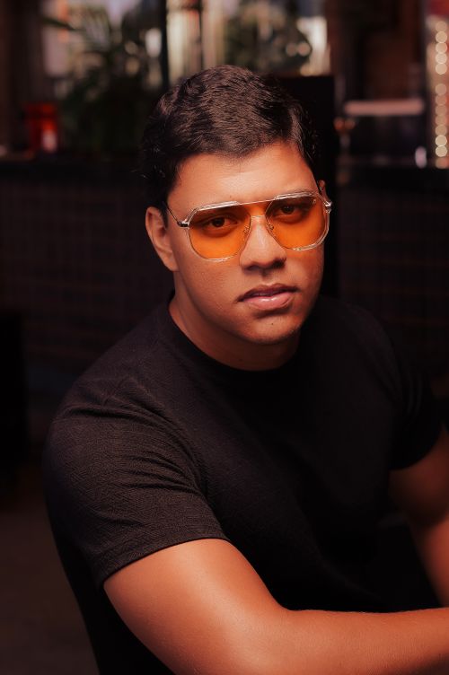 Free A confident man wearing orange sunglasses and a black t-shirt indoors, exuding style. Stock Photo
