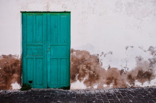 Free Intriguing green wooden door on a vintage, textured wall. Perfect for rustic designs. Stock Photo