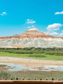 Vibrant striped mountain under a clear sky with lush green surroundings.