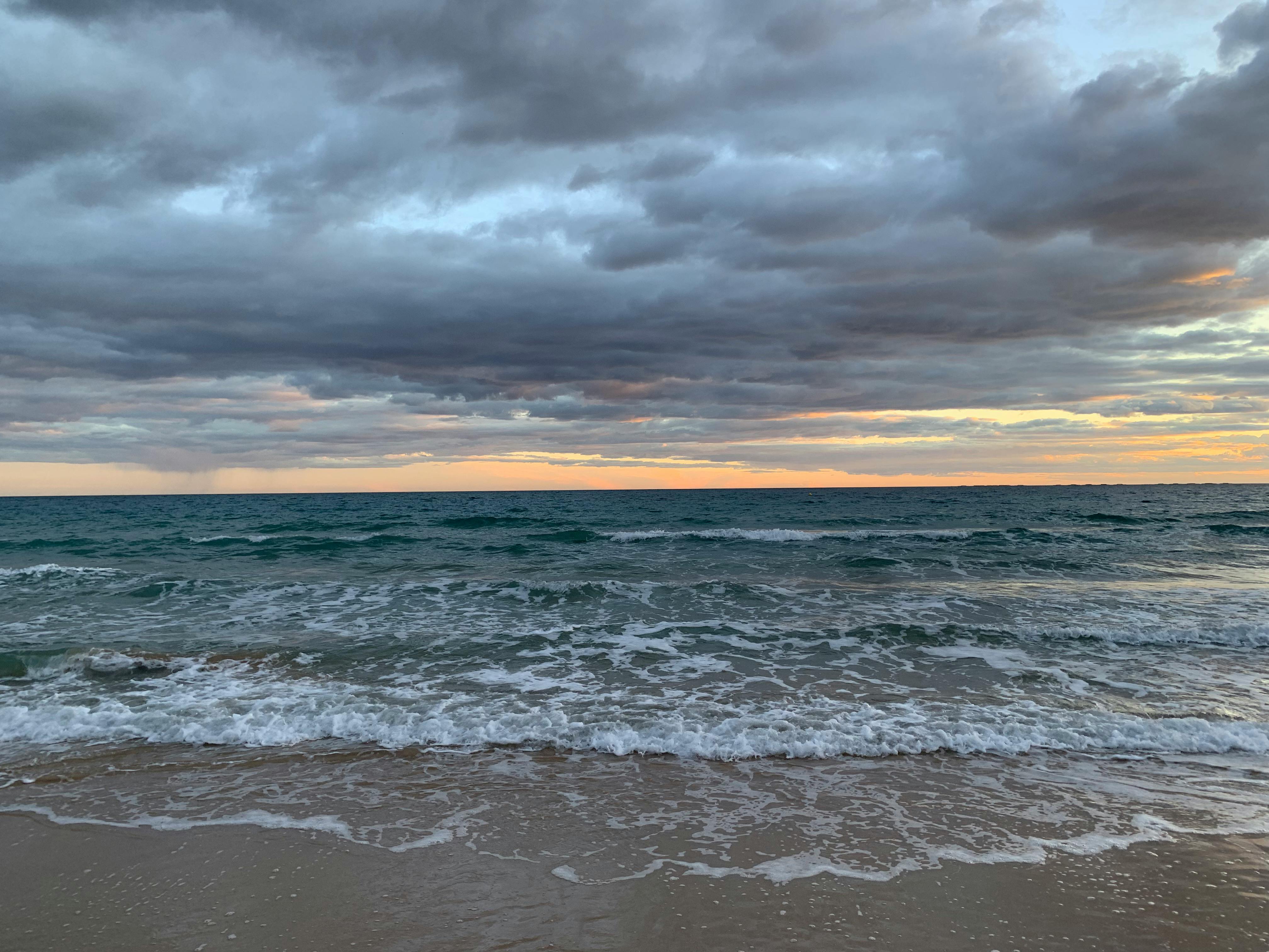 A tranquil evening view of Calp beach with waves and a colorful sky.