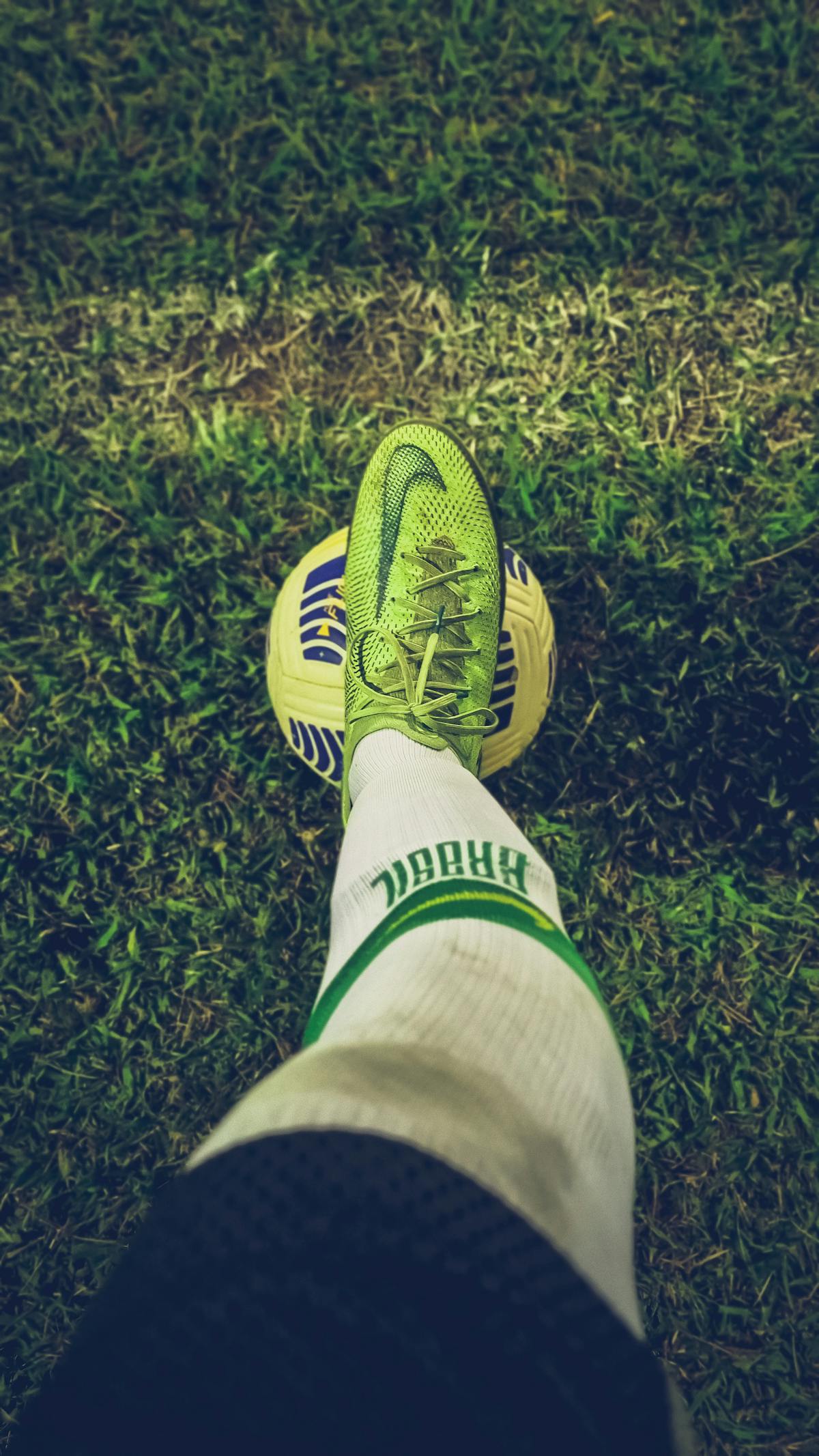 Primo piano di scarpino da calcio appoggiato su un pallone sull'erba