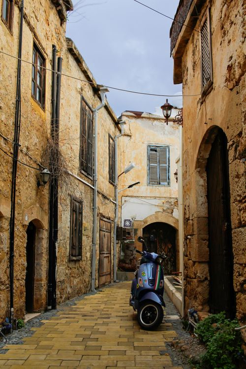 Free Explore the rustic charm of a narrow street in Nicosia with historic stone buildings and warm tones. Stock Photo