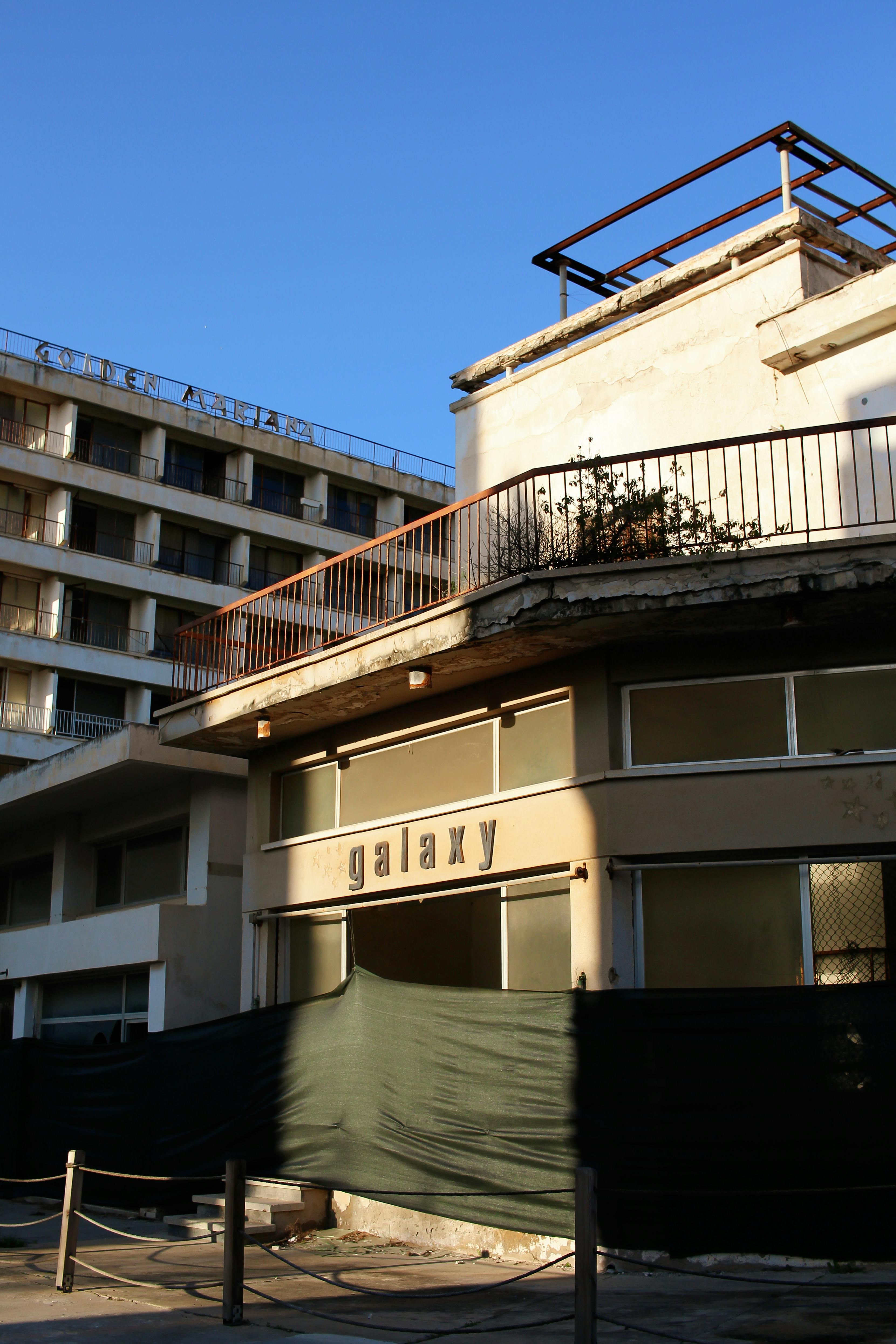An abandoned building with a 'Galaxy' sign under clear blue skies, showcasing urban decay.