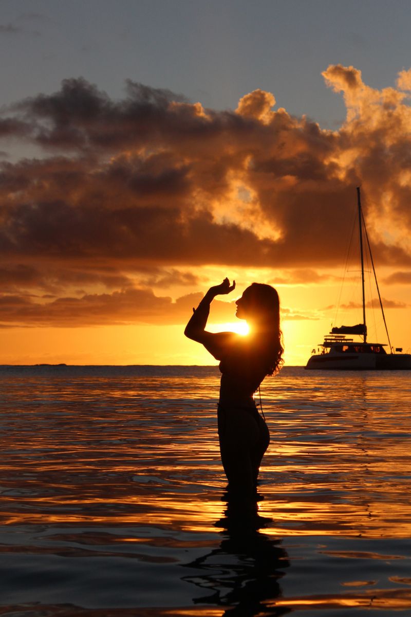 Silhouette au coucher du soleil devant un voilier