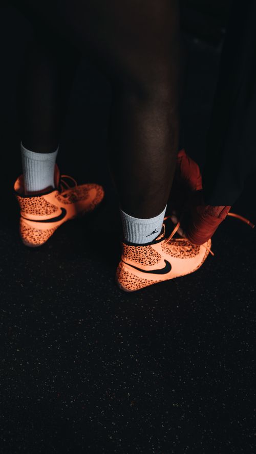 Free Close-up of bright orange sports shoes on a dark gym floor, perfect for fitness-themed content. Stock Photo