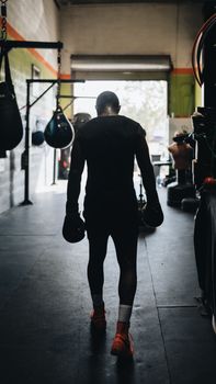 Silhouette of a boxer in a gym, preparing for a training session, daylight.