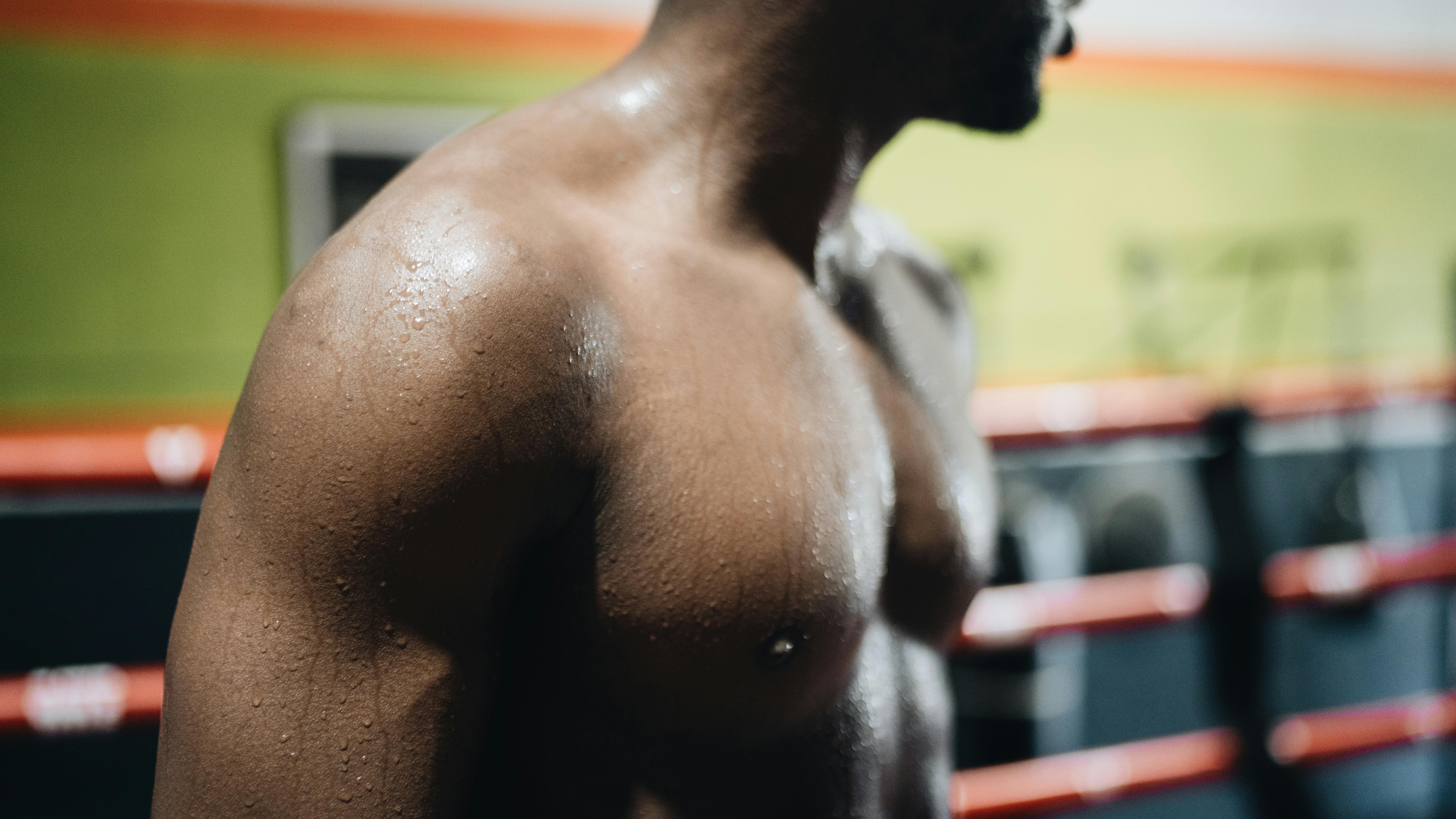 Sweaty and muscular man exercising indoors, showcasing strength and fitness.