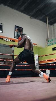 An athlete training hard in a boxing ring inside a gym.