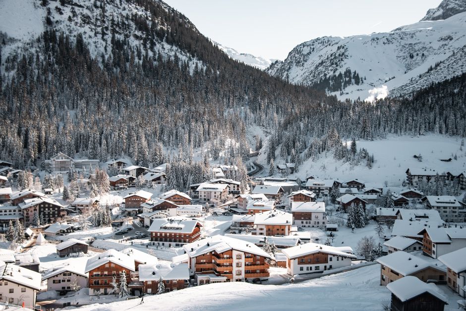 Scenic view of snow-covered village in Lech am Arlberg, Austria with mountains.