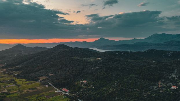 A breathtaking aerial shot of the Dubrovnik-Neretva landscape at sunset, capturing its serene mountains and coastline.