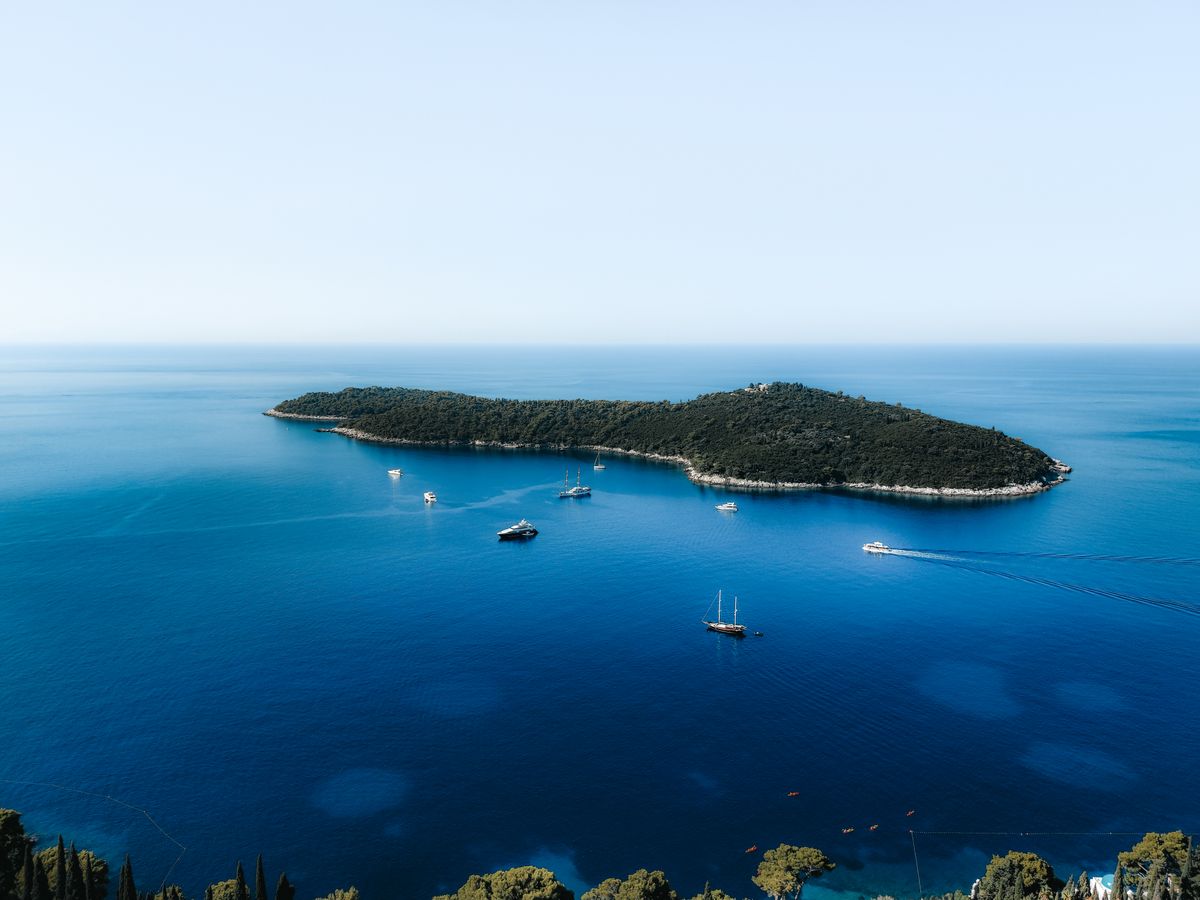 Aerial view of a small Croatian island surrounded by turquoise Adriatic water with boats