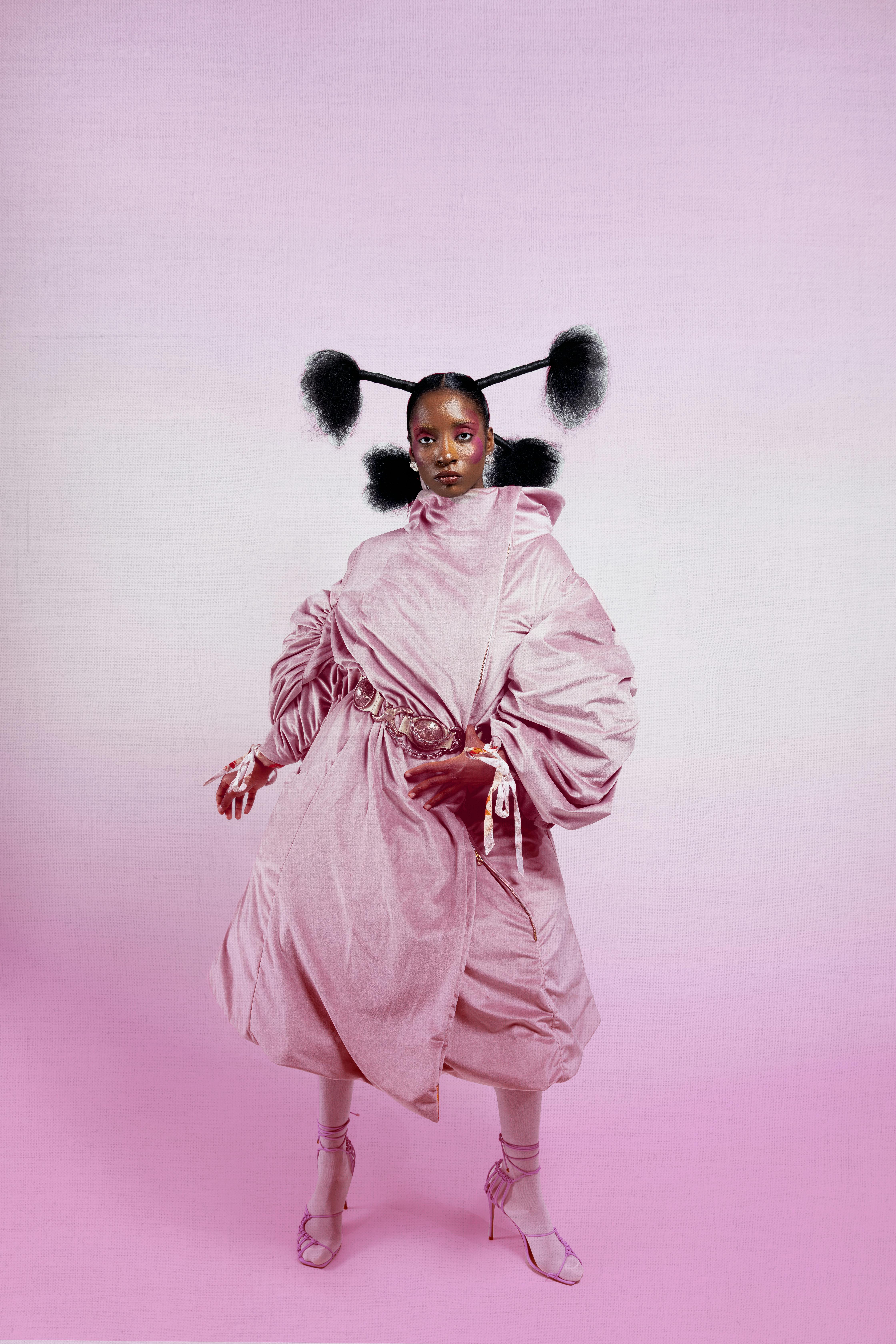 Stylized portrait of a model in avant-garde pink fashion attire with dramatic hair.