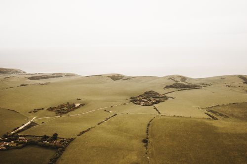 Free Peaceful aerial view of expansive countryside fields and hills under a muted sky. Stock Photo