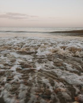 黎明时分，轻柔的波浪与海沫的特写镜头营造出宁静的海滨氛围