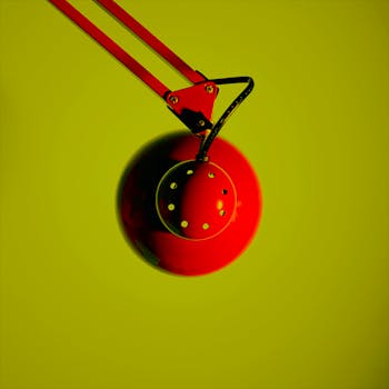 Minimalist red desk lamp with a tilt against a vibrant green background.