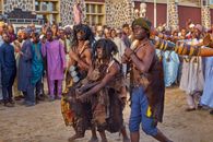 Men in traditional attire performing during a vibrant cultural festival in Africa.