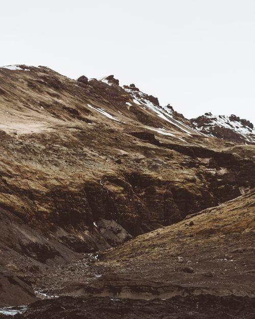 Free Wide view of rugged mountain terrain with sparse snow, embodying raw natural beauty. Stock Photo