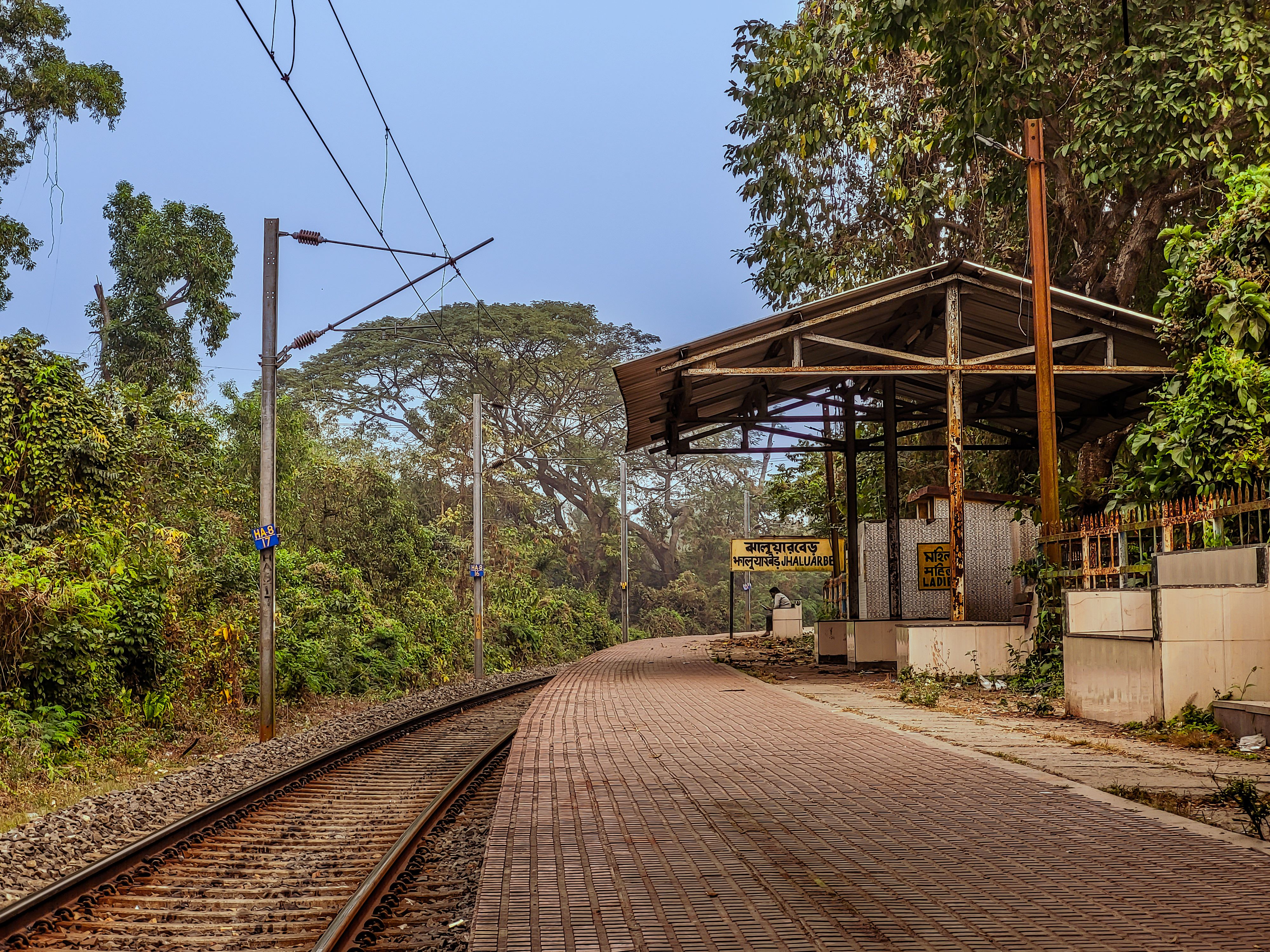 Rustic railway platform in Jhaluarber, West Bengal, India amidst lush greenery. | Indian Village Development