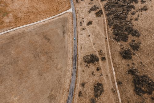 Free Aerial shot capturing a rural road between expansive dry fields and shrubs. Stock Photo