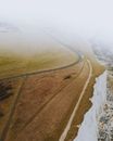 从空中捕捉到的雾覆盖的沿海悬崖和邻近的蜿蜒道路令人惊叹，展现了宁静的景观