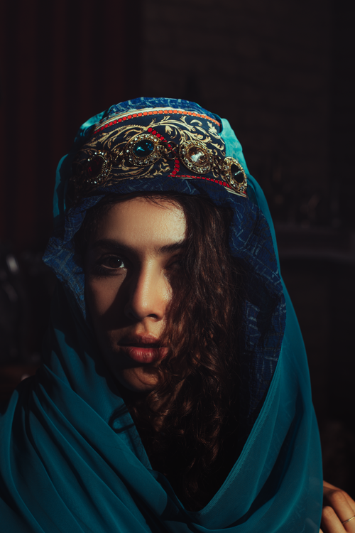 Free A striking portrait of a woman in traditional Middle Eastern attire with rich blues and ornate gold jewelry. Stock Photo