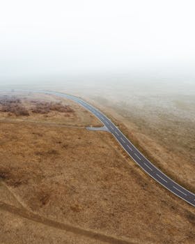 一条蜿蜒的道路穿过雾气缭绕的乡村，景色宁静而安详