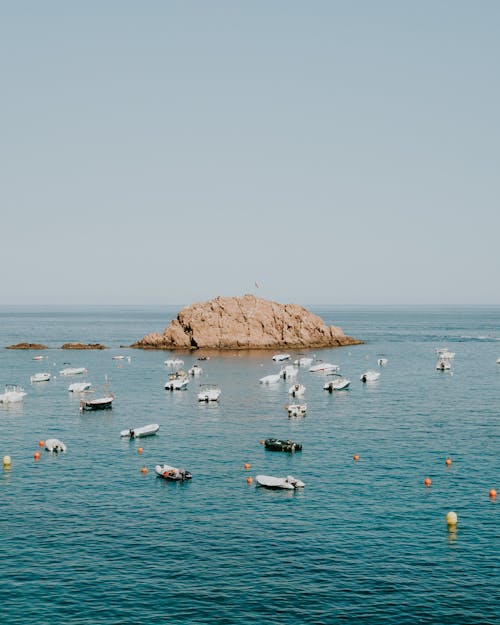 An Offshore Rock Formation Surrounded By Speedboats