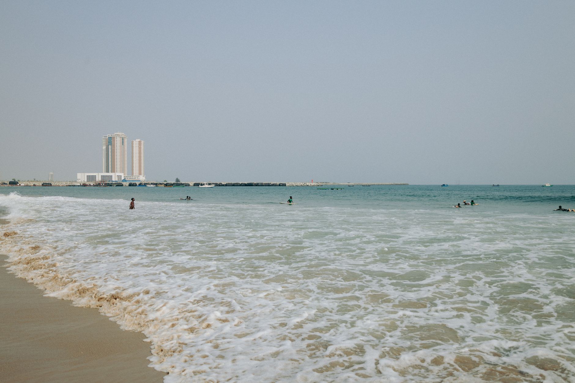 Surfers on a Lagos beach with waves rolling in.