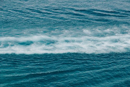 Free A tranquil ocean scene with gentle waves and foamy white patterns, captured during the day. Stock Photo