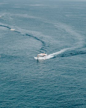 从空中俯瞰，摩托艇在清澈的蓝色海洋上巡航，水中的尾流清晰可见