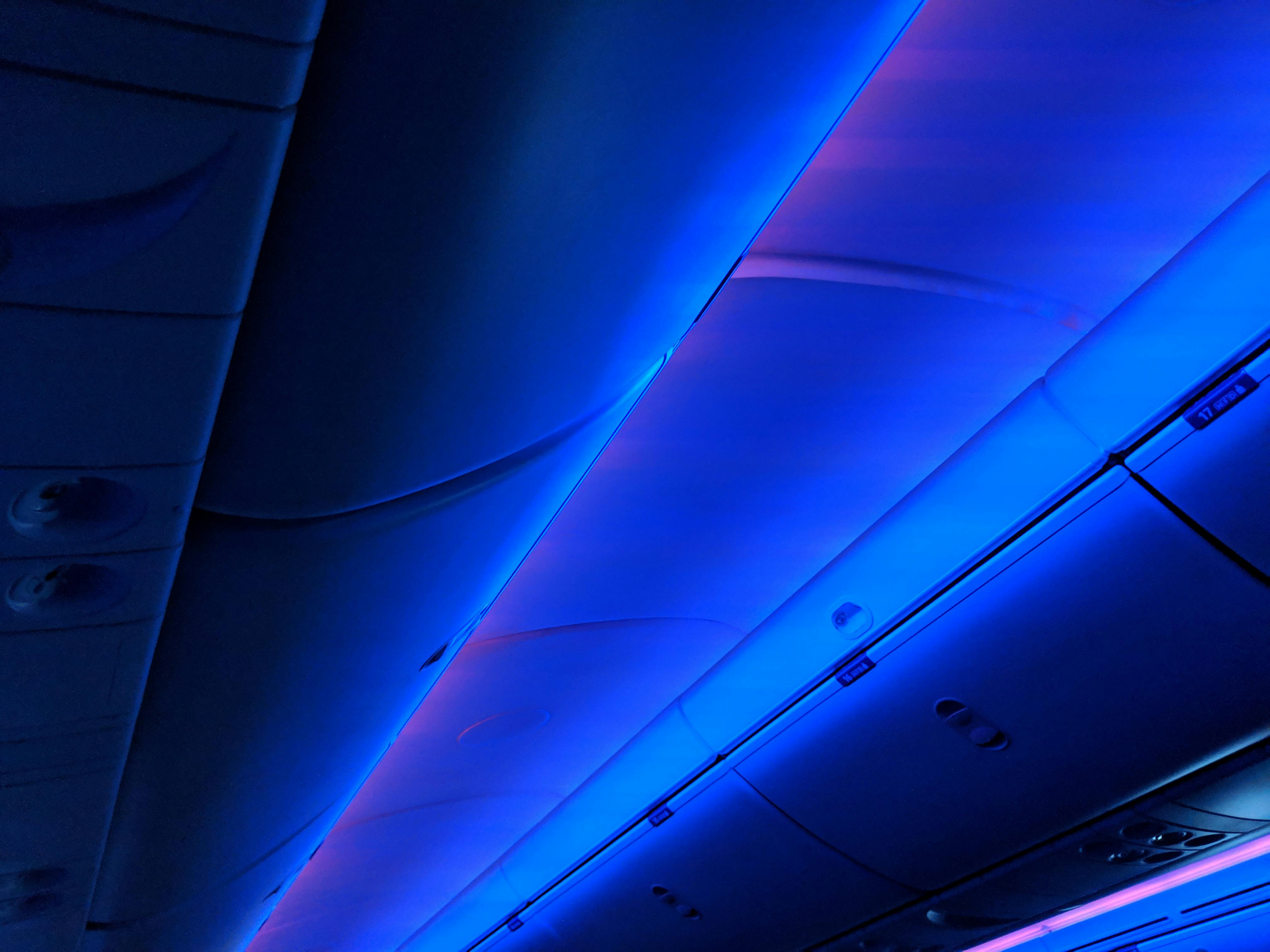 Vibrant blue LED lighting illuminates the sleek design of an airplane cabin interior, highlighting modern travel comfort.