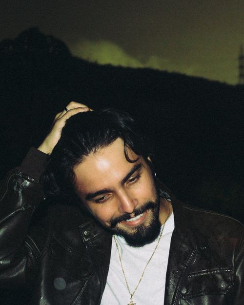Free A candid portrait of a man smiling, wearing a leather jacket outdoors at night. Stock Photo