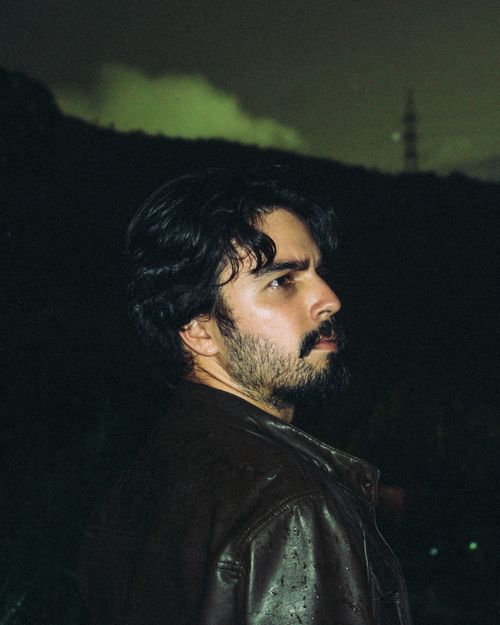Free A moody nighttime portrait of a man in a leather jacket looking pensively to the side. Stock Photo