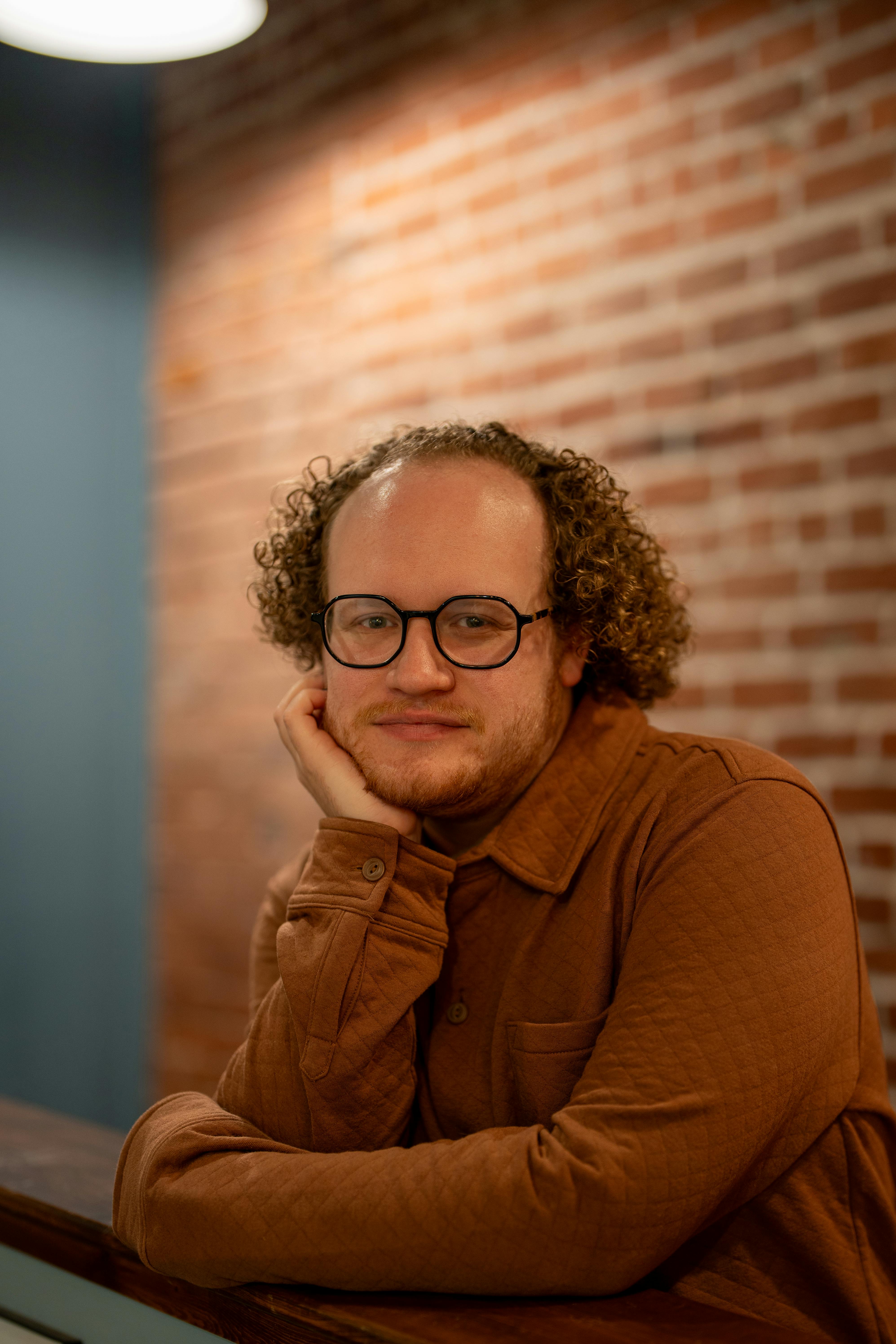 Warm and inviting portrait of a smiling man with curly hair in a cozy coffee shop.