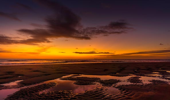 海面上壮丽的日落，倒映在潮湿的沙滩上，与充满活力的天空交相辉映