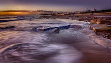 岩石海滩上，日出令人惊叹，背景是沿海小镇，捕捉了风景的自然之美与宁静