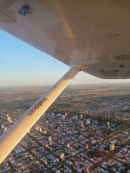 Scenic aerial view of a cityscape through an airplane window during daytime flight.