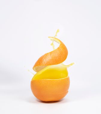 Casca de laranja enrolada ao lado de suco fresco espremido — uso culinário de frutas cítricas