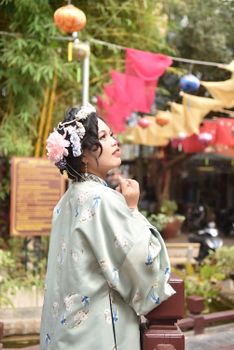 Woman wearing a traditional kimono with floral pattern in a vibrant outdoor setting.