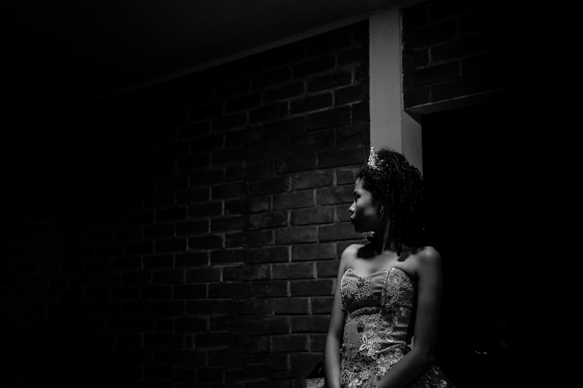 Black and white portrait of a woman in a gown and crown, exuding elegance and mystery.