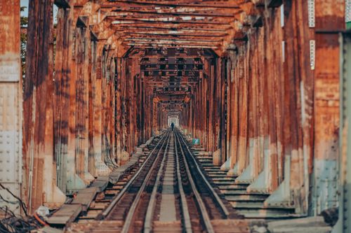Free Rustic railway bridge showcasing a dramatic perspective with leading lines and natural textures. Stock Photo