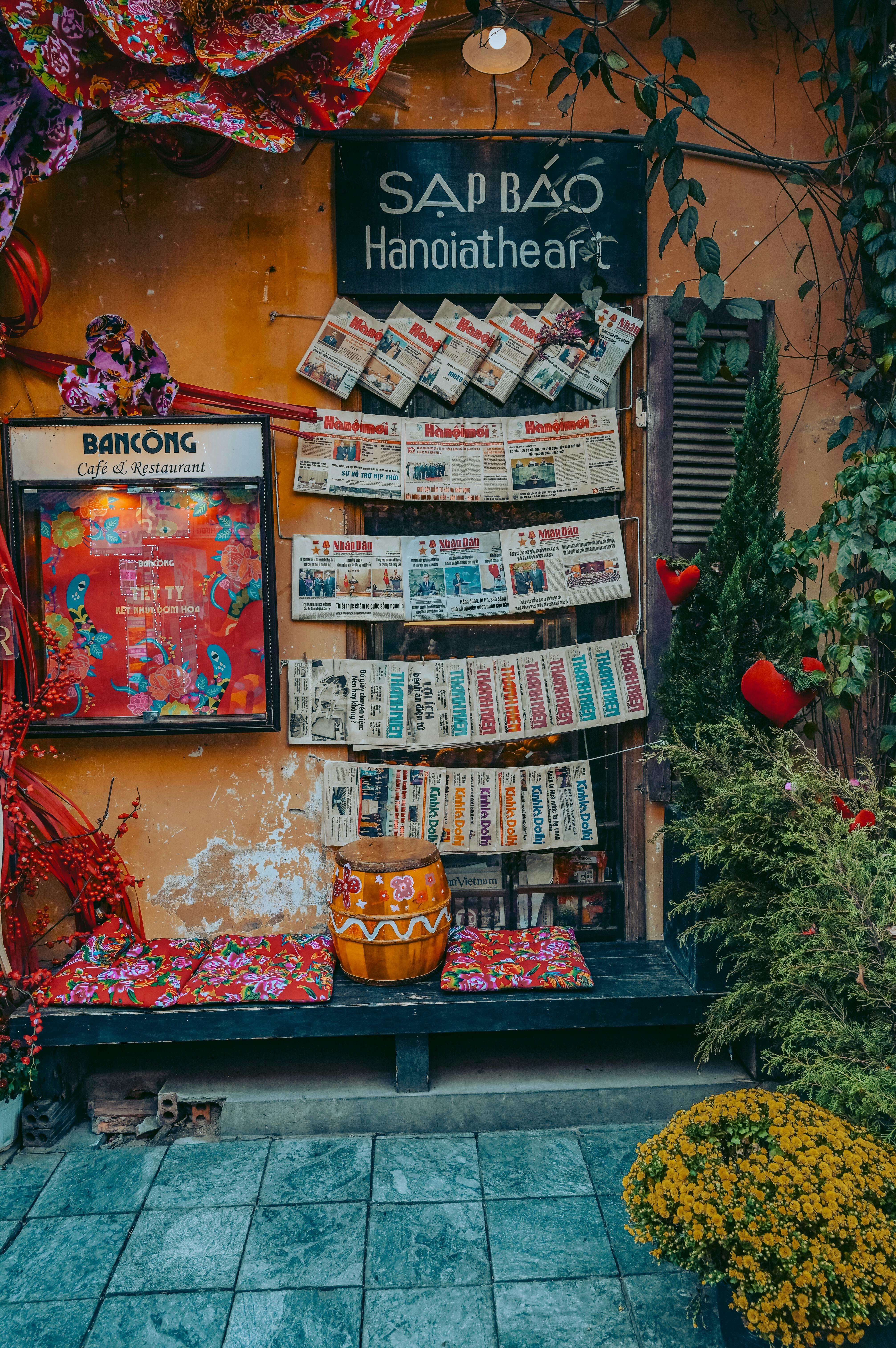 Colorful Vietnamese newsstand adorned with hanging newspapers and vibrant decor in an outdoor setting.