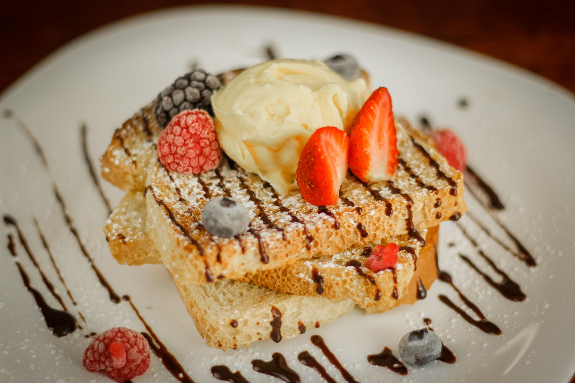 Golden Bourbon Ball French Toast topped with strawberries and whipped cream