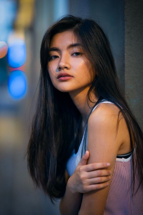 Free Beautiful young woman with long hair posing outdoors during twilight with a subtle expression. Stock Photo