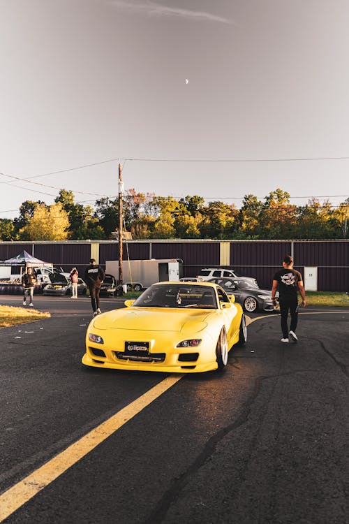 бесплатная Человек идет рядом с желтым спортивным автомобилем Стоковое фото