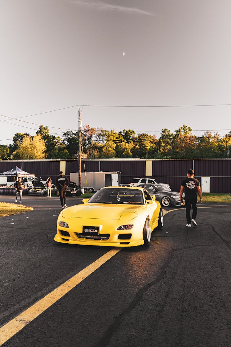 Man Walking Beside A Yellow Sports Car