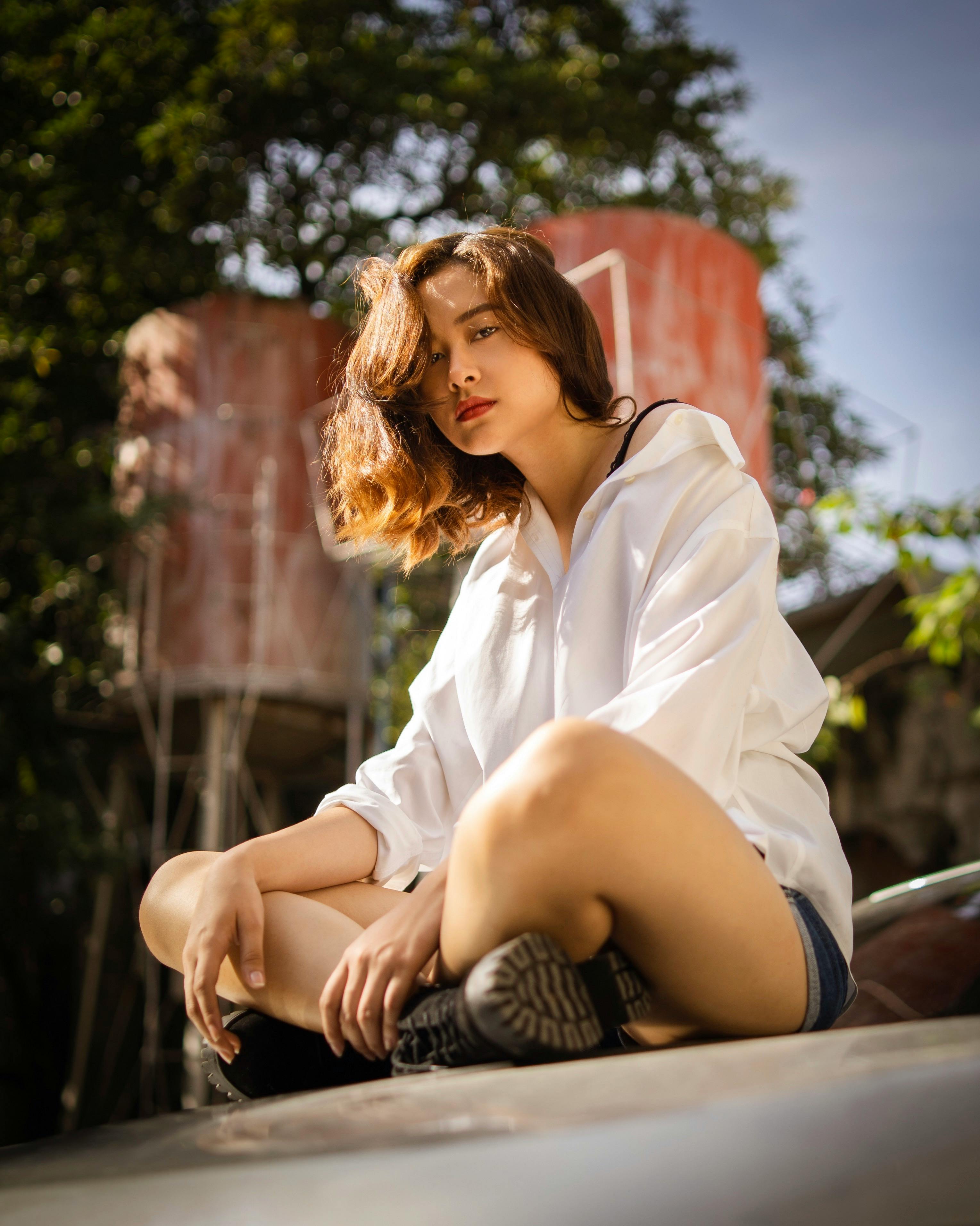 一位年轻女子穿着休闲装，自信地坐在户外，享受着阳光明媚的一天