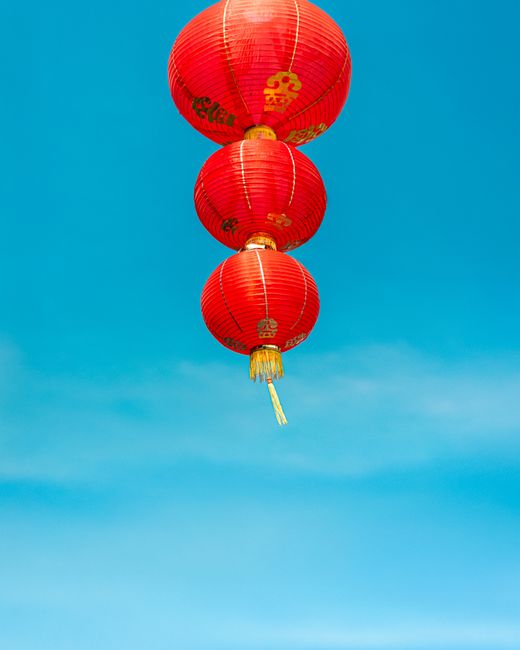 Red Chinese lanterns floating against a clear blue sky, symbolizing celebration and festivity.