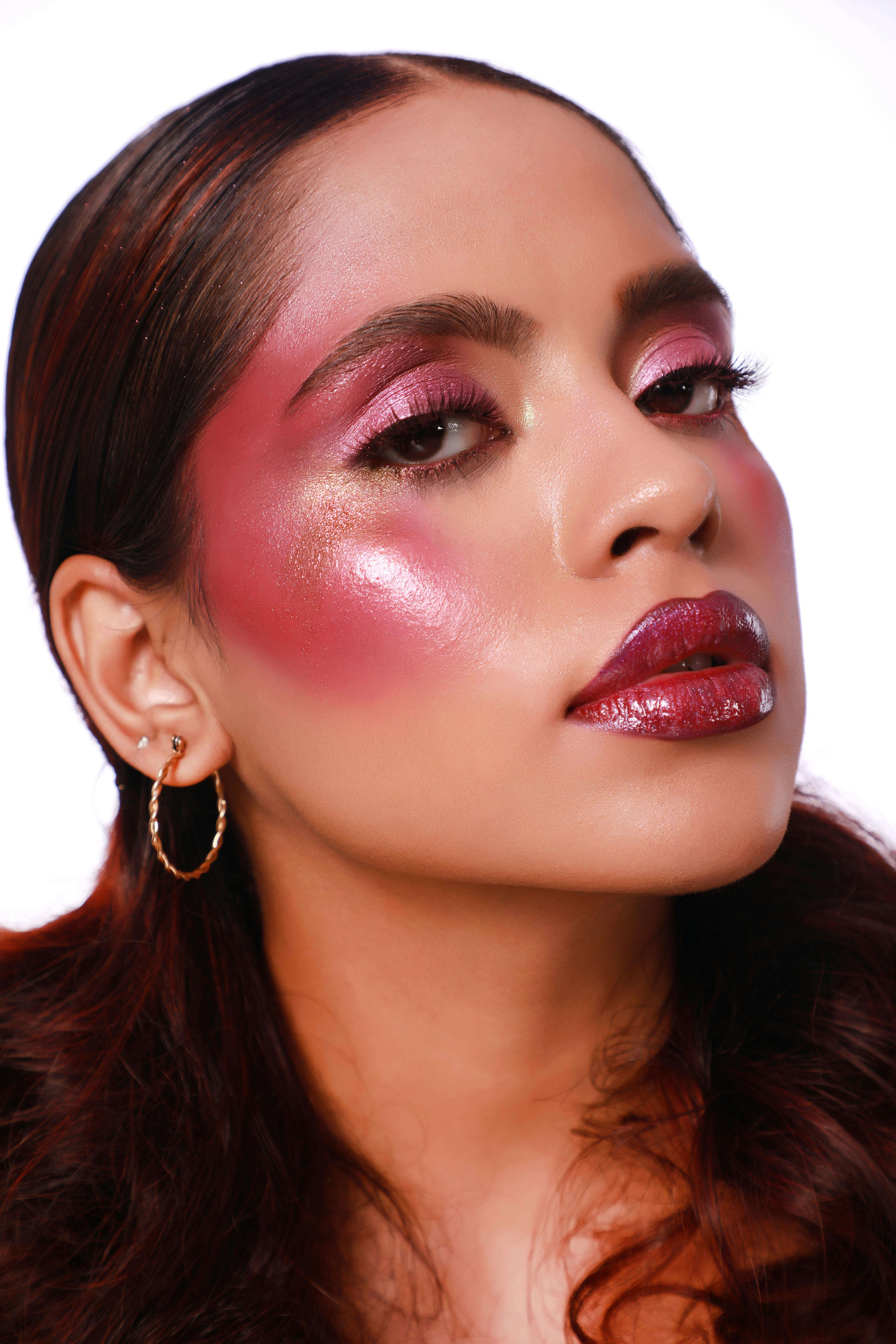 Close-up portrait of a woman featuring bold, dramatic makeup with shimmering highlights.