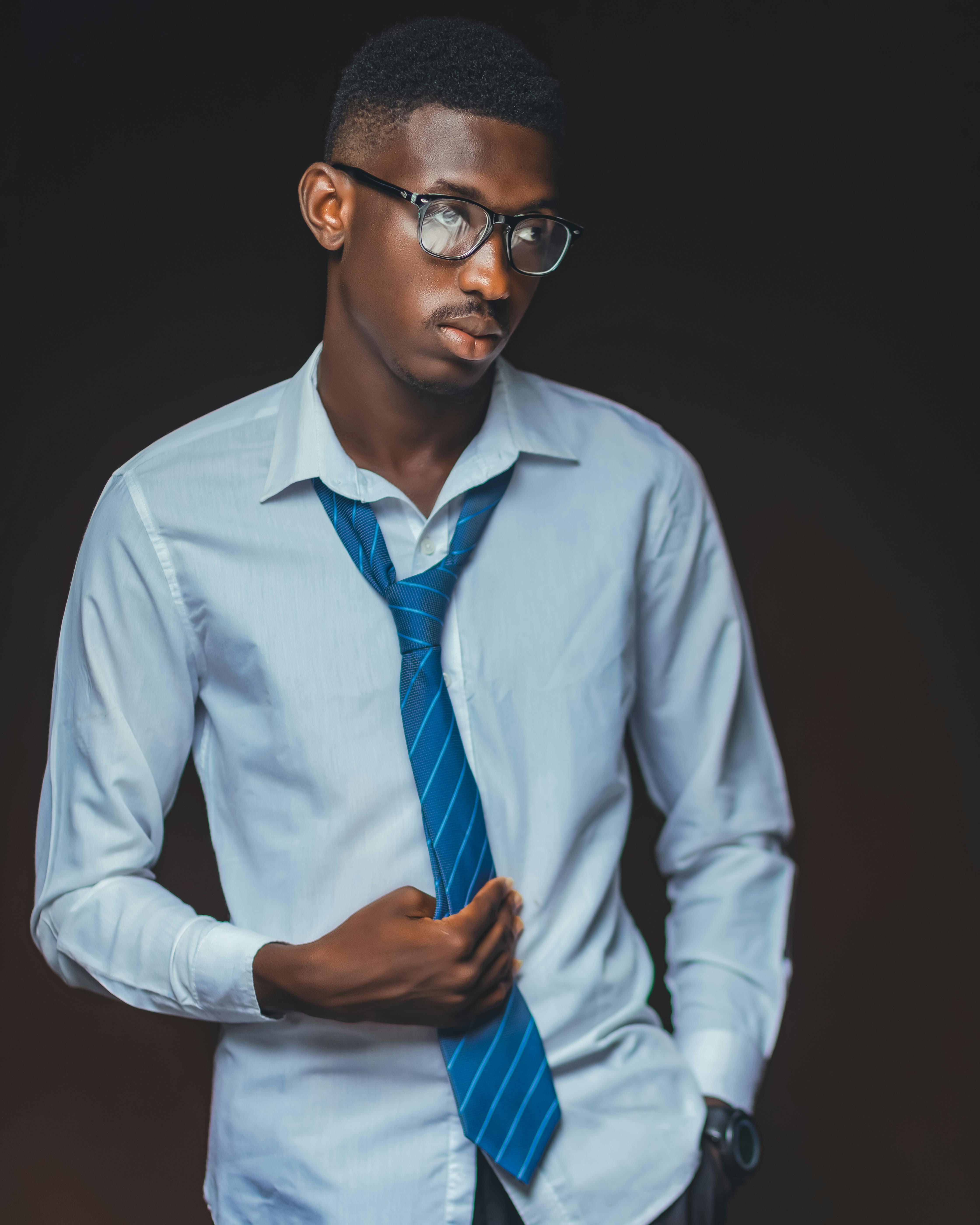Professional portrait of a stylish young man in Accra, Ghana wearing a blue tie and glasses.